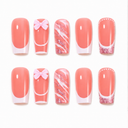 Ten coral pink glitter swirl and French bow coffin nails neatly arranged on white