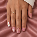 Dusty pink gold bow and white floral square nails worn against pink satin