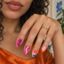 Bright pink blue and orange tropical petal almond press-on nails — worn on hand