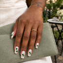 Green shamrock and silver flake square nails worn with a sage linen clutch