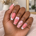 Pink marble French bow coffin nails worn on a naturally curled hand against blush linen