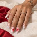 Red floral white French almond nails worn against ivory linen and red fabric