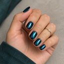Short teal cat-eye squoval press-on nails on a softly curled hand with a delicate silver ring