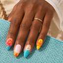 Tropical floral and starfish almond nails worn against a turquoise beach bag